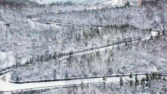 鸟瞰图弯曲的山路上山穿过松树和其他树木覆盖在冬天的雪山在四川西岭