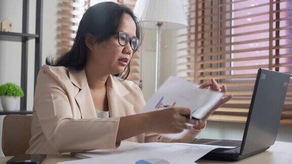 亚洲女性与商业计划图表纸会议视频会议上的笔记本电脑在家里工作