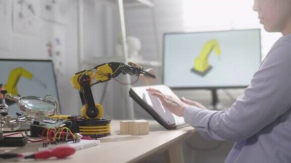 女工程师正在他的车间里研究创新技术机械机器人手臂她用数字平板电脑用手控制机器人手臂
