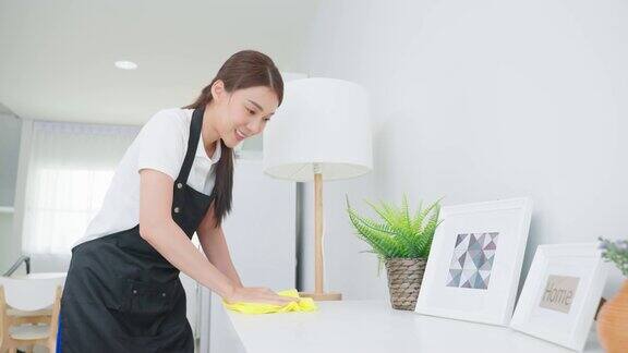 亚洲清洁服务女工清洁客厅在家里美丽的女孩主妇管家清洁工感到高兴并擦拭脏乱的工作台面为家政家务或杂务