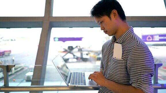 一名男子在机场候机厅使用笔记本电脑