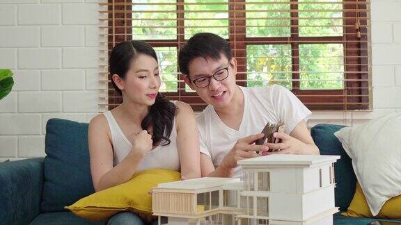 一对亚洲夫妇正在为他们的新房子项目审查房子模型选择墙壁颜色规划室内装饰