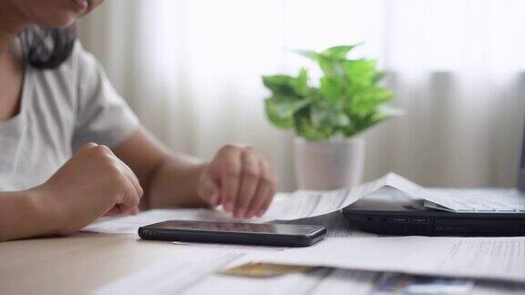 压力大的亚洲年轻女性管理财务和信用卡账单在家里用手机计算家庭财务债务一个做开支计划的妻子