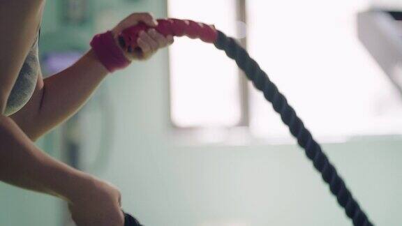 一名年轻女子在健身房用战绳锻炼