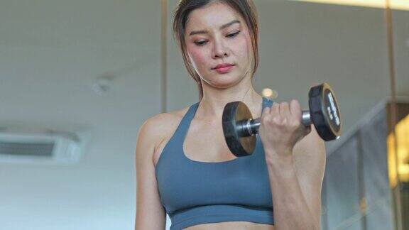 亚洲妇女在健身房用哑铃锻炼