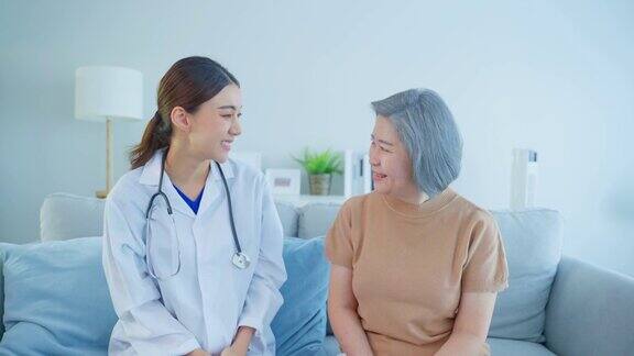 老年女病人与医生坐在一起的画像看护者治疗师药剂师女孩拜访并给予诊断服务治疗老年女性微笑看着相机