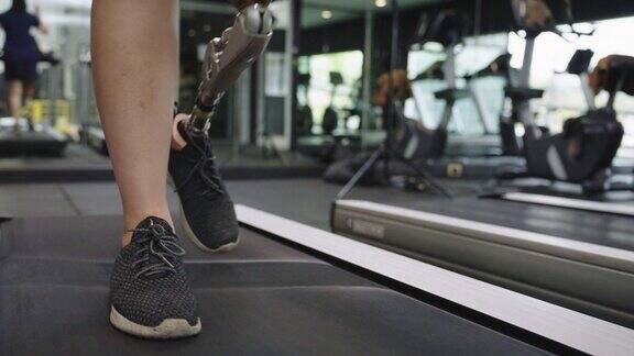 年轻女性与膝盖以上的腿假体或假体运动在健身房的跑步机上