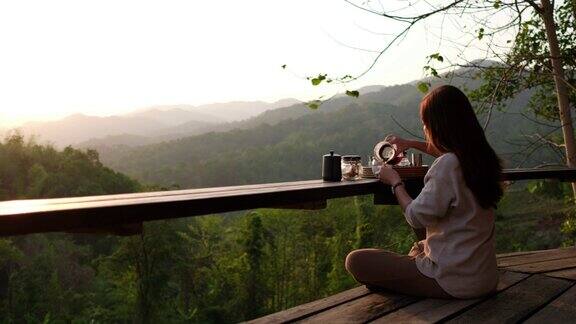 一个女人的后视图和一个美丽的自然景色在早上制作和喝滴咖啡