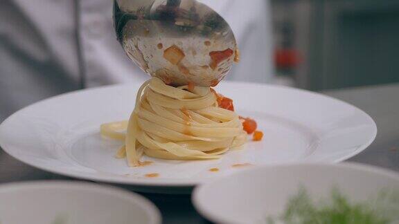 厨师正在把意大利面酱倒在盘子里的面条上
