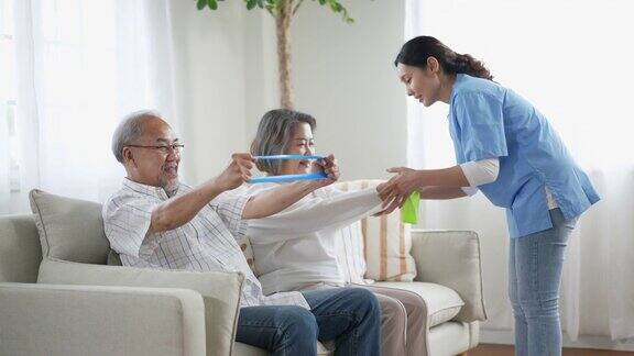 老年夫妇退休后在家里和教练一起通过健身带进行锻炼