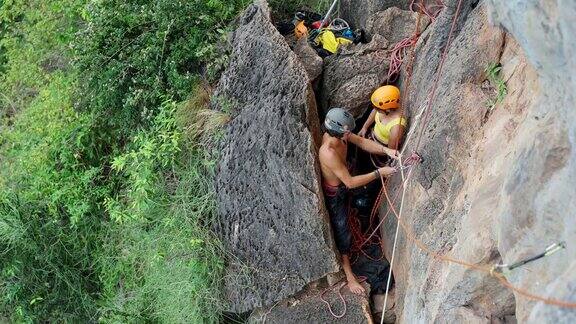 4K亚洲男人和女人在攀登热带岛屿上的落基山时互相帮助