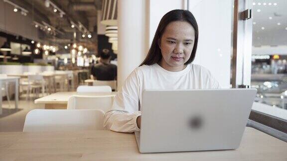在咖啡馆用笔记本电脑工作的亚洲女性