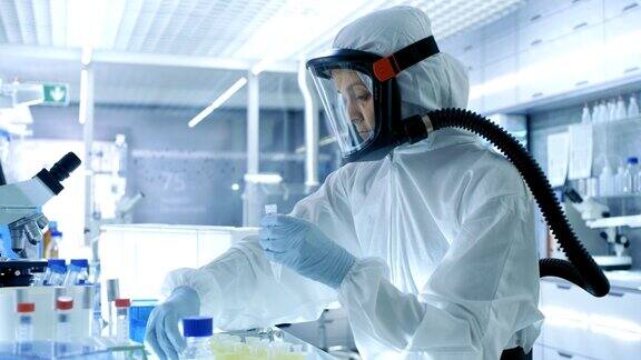 医学病毒学研究科学家工作在一个危险防护服与口罩她从冰箱盒子拿出试管和使用微管她在一个无菌的高科技实验室工作研究设施