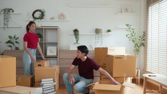 一对亚洲年轻的成年夫妇正在协助携带包裹进入新房子和安排东西