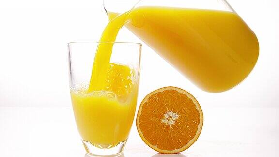 在白色背景下将橙汁倒入玻璃中慢动作4K