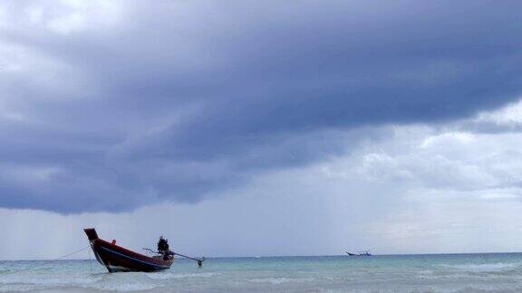 在浅海中长尾船在海滩附近摆动背景是泰国的风暴云
