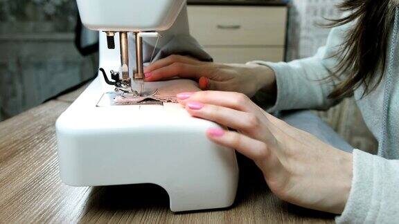 女裁缝把织物和缝纫它在缝纫机上的特写