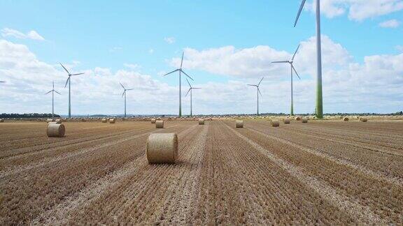 在林肯郡农民新收获的田地里风力涡轮机旋转一幅迷人的画面在高空展开金色的干草捆使画面更加完整
