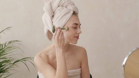 浴袍女子用玉面辊进行皮肤护理在家进行美容治疗