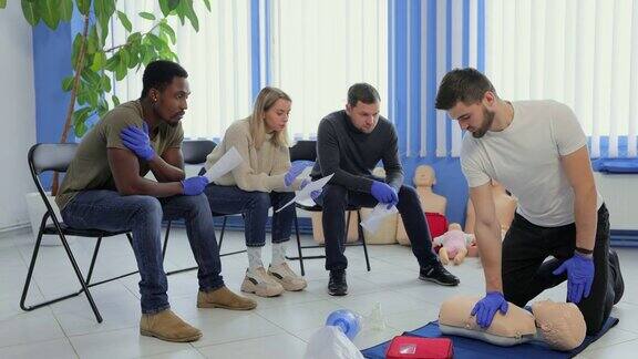 男子教练在室内急救小组训练中演示如何用假人做胸部按压
