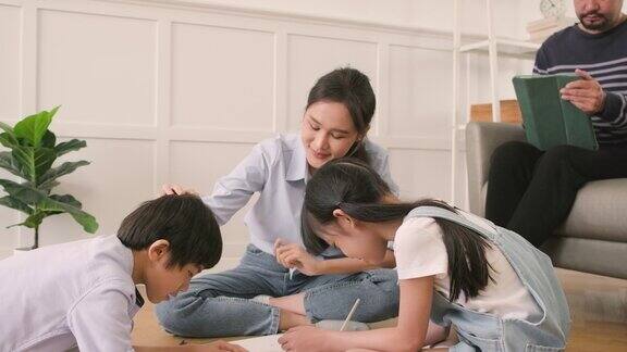 亚洲家庭休闲用彩色铅笔一起在客厅地板上画画