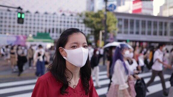 年轻女子身穿红色衣服戴着防护面罩走在涉谷十字