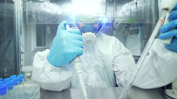 科学家在实验室里穿着防护服拿着显微镜和微移液器工作