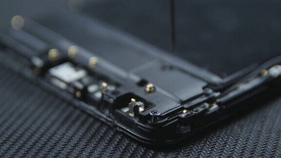 手机维修过程的特写镜头修理工用螺丝刀取出螺丝智能手机的内部组件拆卸手机副本的空间