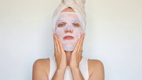 面部护理和美容护理皮肤柔软光滑美容和美容呵护皮肤护理程序一名女子在白色背景下脸上敷着保湿面膜头上缠着浴巾