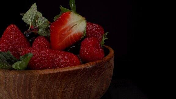 黑色背景木碗里的静态旋转森林水果草莓蓝莓覆盆子健康水果4K镜头