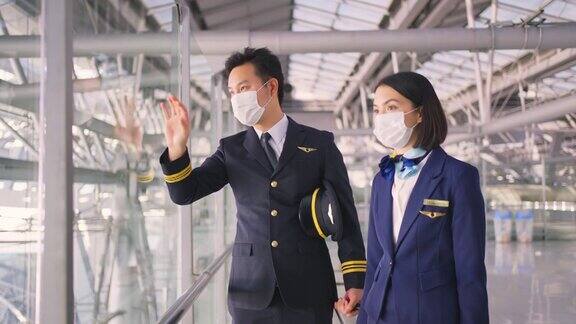 新冠肺炎疫情期间飞行员和空乘人员戴口罩走在机场航站楼走向飞机以预防新冠肺炎感染航空运输的新常态生活理念