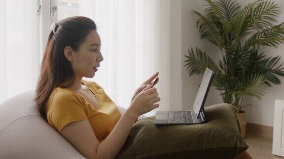 年轻的亚洲妇女购物笔记本电脑与信用卡