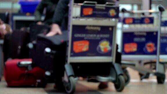 机场安检在入口处进行行李检查扫描的行李携带红色大而重的行李箱的家庭通过入口管制将行李装上手推车