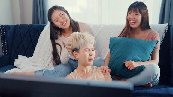 年轻的亚洲女性朋友一起坐在家里的沙发上看电视共度周末
