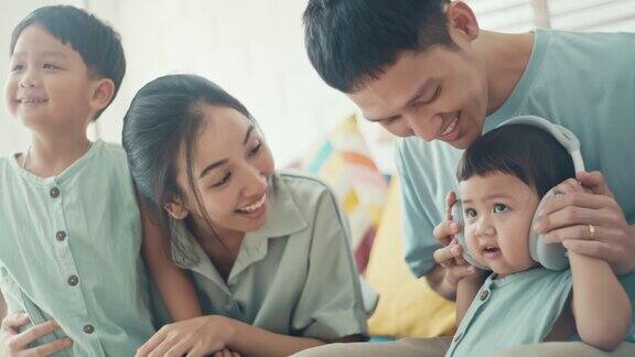 快乐的亚洲家庭在家里用耳机慢动作
