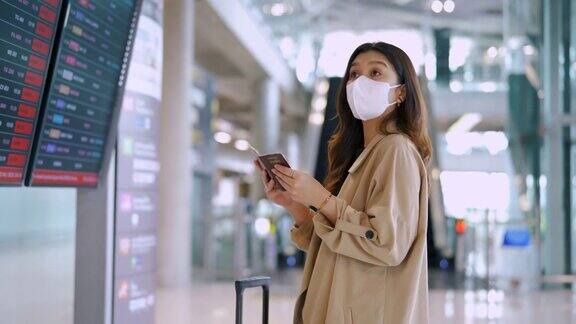 旅客在机场戴着口罩看航班时刻表