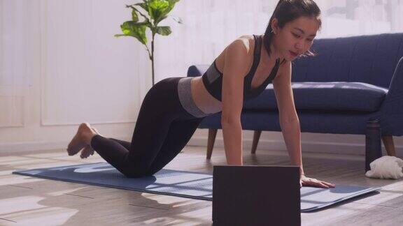 亚洲妇女穿着运动服做俯卧撑在运动垫上锻炼