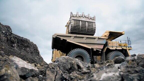 一辆大型黄色挖掘机将矿石和泥土装进一辆自卸卡车一个采石场适用于矿石4K
