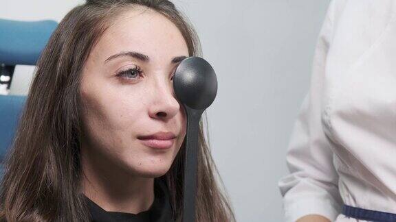 细心的验光师检查一位美丽的女病人在眼科诊所用一个闭塞器检查她的视力现代诊所的检查病人的特写侧视图