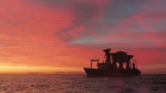 科学船与卫星天线剪影在海上浪漫的日落照明