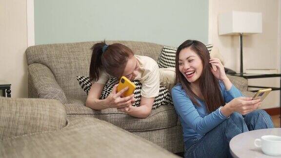 亚洲女性朋友一起在客厅用智能手机玩游戏