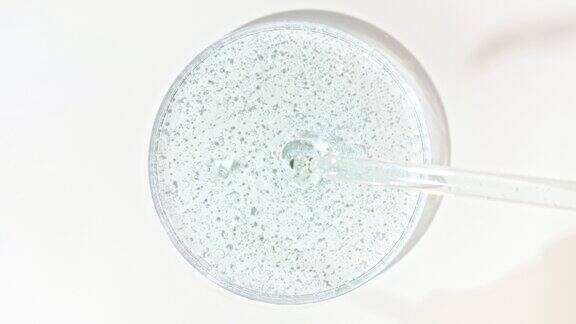 透明化妆品凝胶液从移液管滴入有培养皿的玻璃碗中微距拍摄的化妆品精华液透明尿酸皮肤护理概念