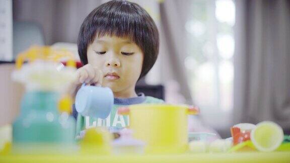一个男孩在家里客厅的桌子上玩厨房的玩具