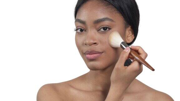 迷人的非洲裔美国女人使用化妆刷化妆粉美丽孤立在白色背景上