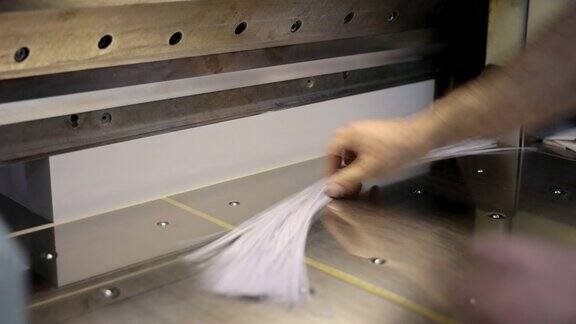 在印刷厂里一位面目全非的白人工人正在数控切割机上裁纸