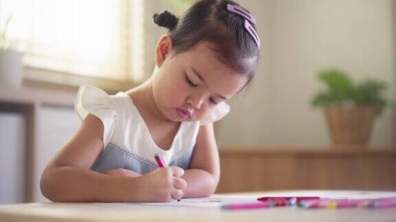 亚洲小女孩喜欢在家里的客厅用彩色蜡笔在纸上画画幼儿技能发展活动周末在家学习艺术
