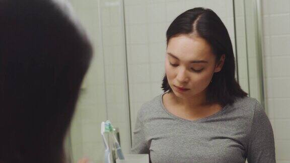 漂亮的亚洲女人在浴室里梳头