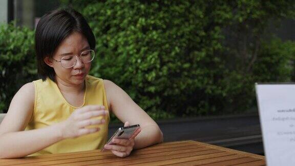 短发的女游客戴着眼镜坐在咖啡厅里用触摸智能手机在网上购物和社交媒体上搜索旅游信息长周末的活动让女性感到放松和快乐