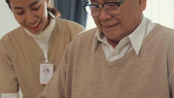 特写年轻的亚洲女性护理人员教老男性步行使用助行器照顾握着老人的手在家里