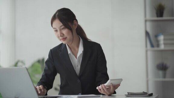 年轻的亚洲商业女性在办公室的笔记本电脑上工作桌上有文书文件